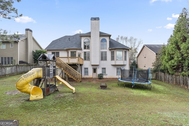 rear view of house with a playground, a trampoline, and a yard