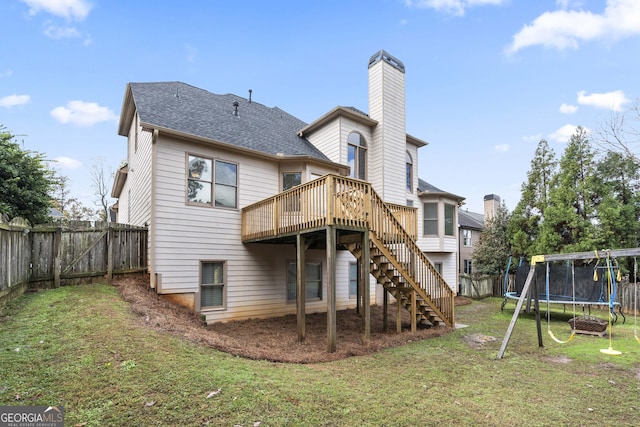 back of property featuring a lawn, a trampoline, and a wooden deck