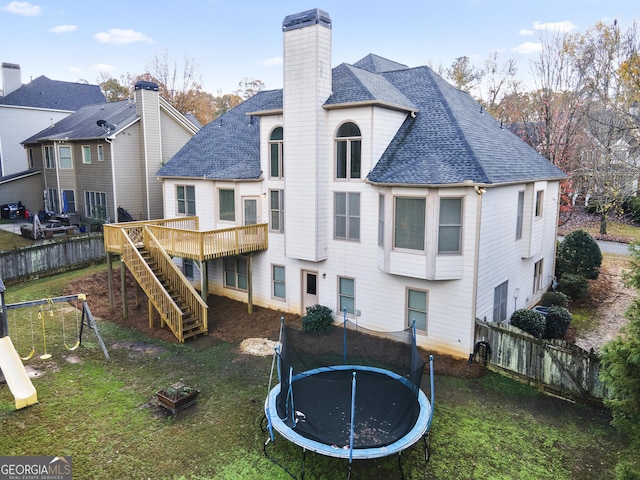 rear view of house featuring a yard, a deck, and a trampoline