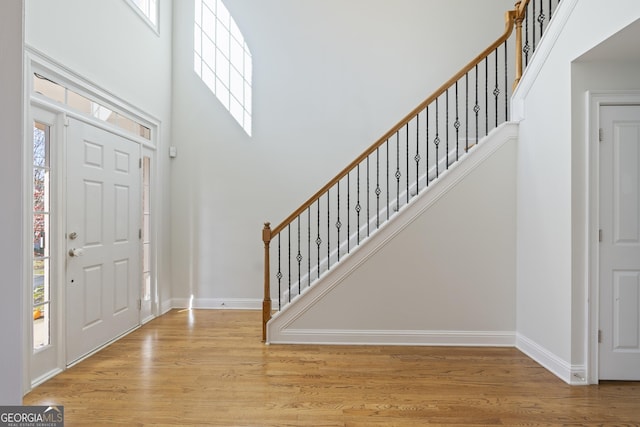 entryway with plenty of natural light, light hardwood / wood-style floors, and a towering ceiling