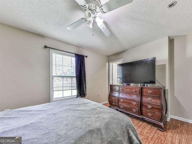 bedroom featuring ceiling fan, light wood-type flooring, and a textured ceiling