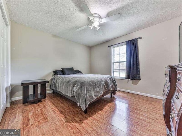 bedroom with ceiling fan, wood-type flooring, and a textured ceiling