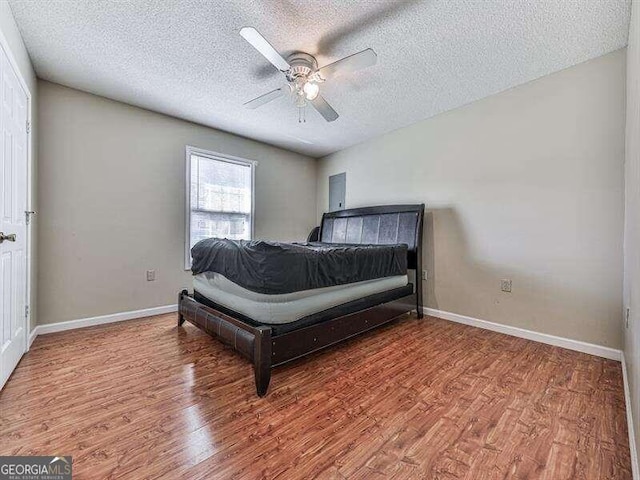 bedroom with ceiling fan, wood-type flooring, and a textured ceiling