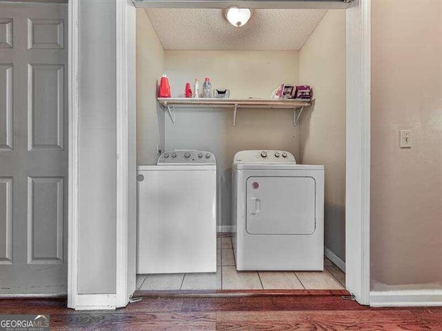 laundry area featuring a textured ceiling, light wood-type flooring, and washing machine and clothes dryer