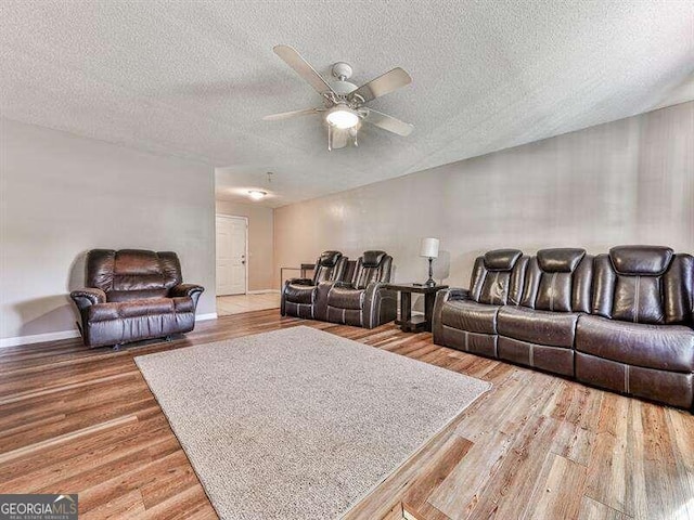 living room featuring wood-type flooring, a textured ceiling, and ceiling fan