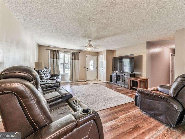 living room featuring ceiling fan, wood-type flooring, and a textured ceiling