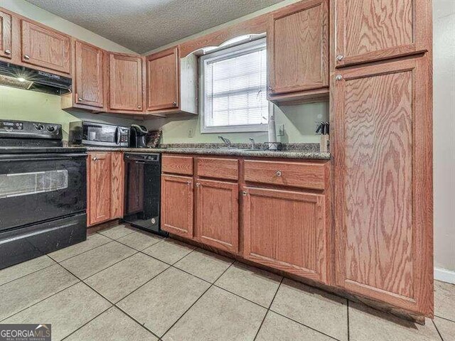 kitchen with a textured ceiling, light tile patterned floors, black appliances, and extractor fan