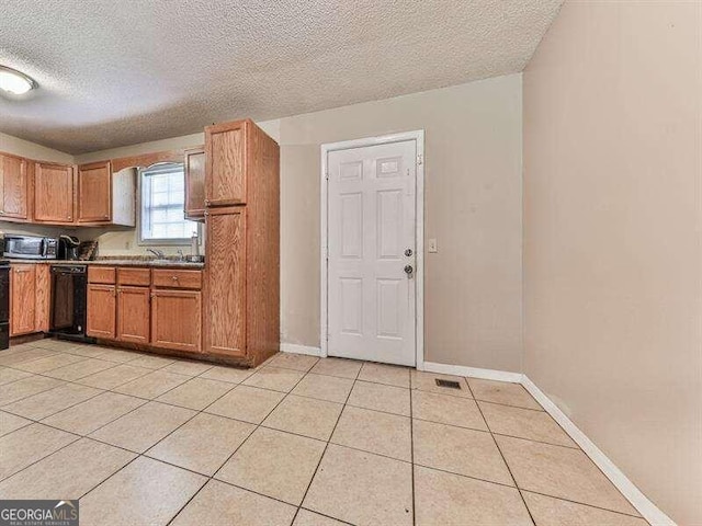 kitchen featuring a textured ceiling, black dishwasher, and light tile patterned flooring