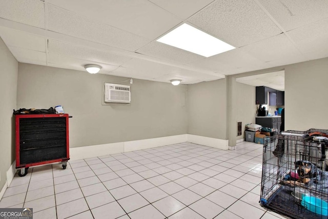 basement featuring a wall mounted air conditioner, a drop ceiling, and light tile patterned floors