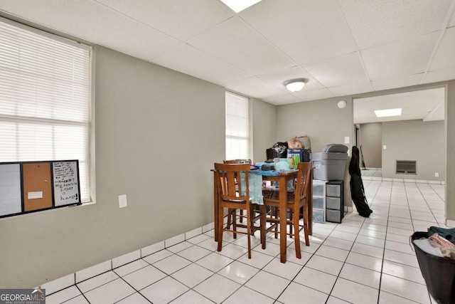 dining space featuring a paneled ceiling and light tile patterned floors