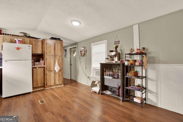 kitchen with wood-type flooring, white refrigerator, a textured ceiling, and lofted ceiling