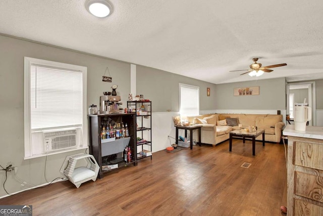 living room with a textured ceiling, ceiling fan, cooling unit, and dark wood-type flooring