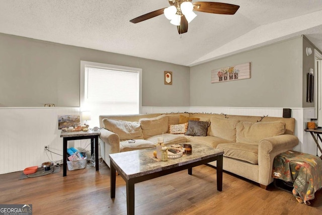 living room with a textured ceiling, hardwood / wood-style flooring, ceiling fan, and lofted ceiling