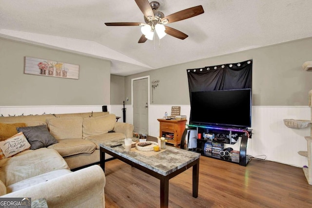 living room featuring ceiling fan, wood-type flooring, and vaulted ceiling