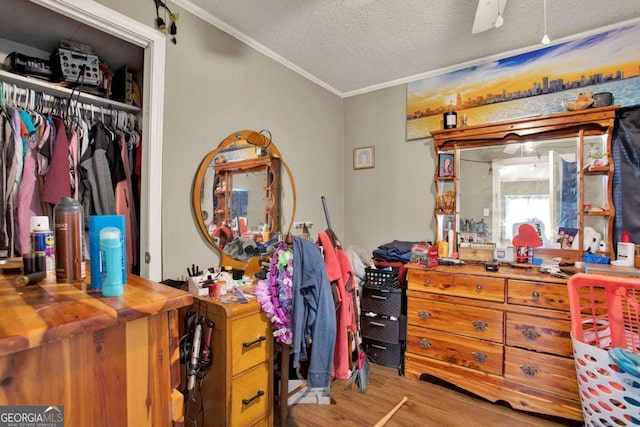 bedroom featuring a textured ceiling, light wood-type flooring, a closet, and ornamental molding