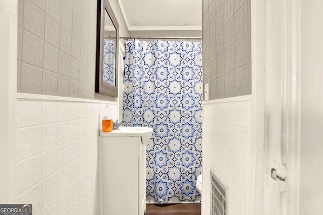 bathroom with vanity, toilet, a textured ceiling, tile walls, and wood-type flooring