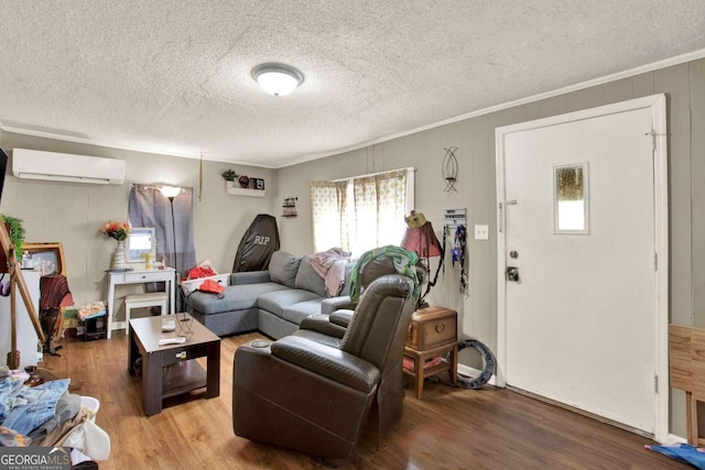 living room featuring a textured ceiling, ornamental molding, a wall mounted air conditioner, and hardwood / wood-style flooring