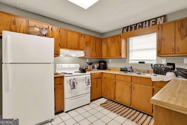 kitchen with light tile patterned flooring, white appliances, and sink