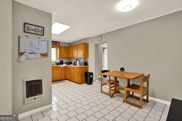 kitchen with a paneled ceiling, heating unit, and light tile patterned flooring