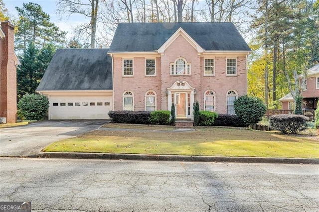 colonial house featuring a garage and a front lawn