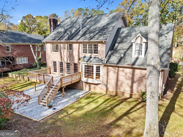 back of property featuring a wooden deck and a lawn