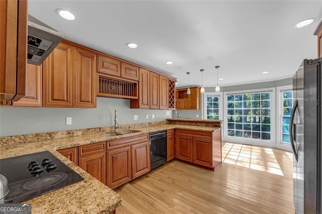 kitchen with kitchen peninsula, sink, black appliances, pendant lighting, and light hardwood / wood-style floors