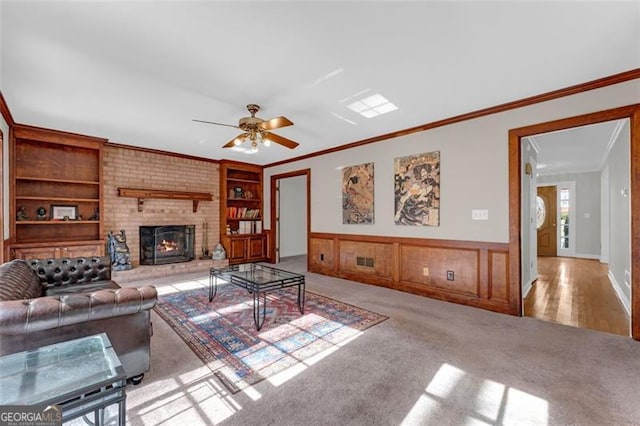 living room featuring built in shelves, light hardwood / wood-style floors, ornamental molding, and a fireplace