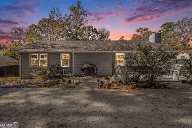 back house at dusk featuring a patio