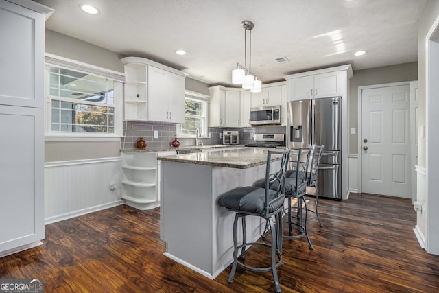 kitchen featuring dark stone countertops, white cabinets, dark hardwood / wood-style floors, and appliances with stainless steel finishes