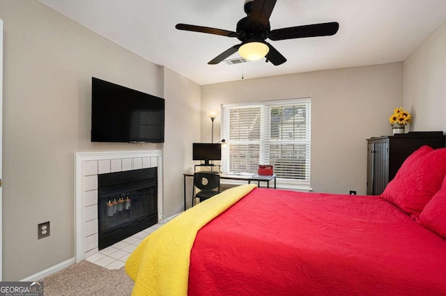 tiled bedroom with ceiling fan and a fireplace