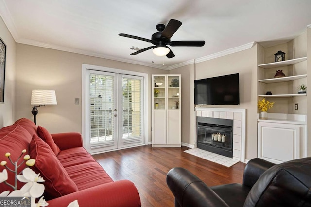 living room featuring a fireplace, ceiling fan, crown molding, and dark wood-type flooring