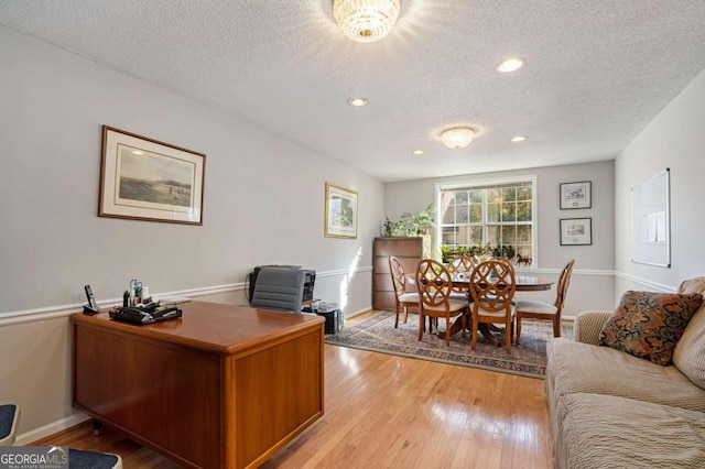 home office with a textured ceiling and light wood-type flooring