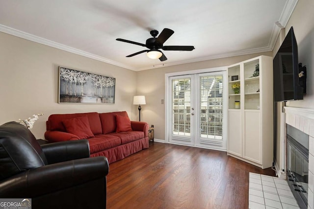 living room with a tile fireplace, crown molding, ceiling fan, and dark hardwood / wood-style floors