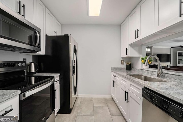 kitchen with white cabinets, stainless steel appliances, light stone counters, and sink