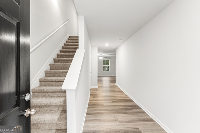 staircase with ceiling fan and hardwood / wood-style floors