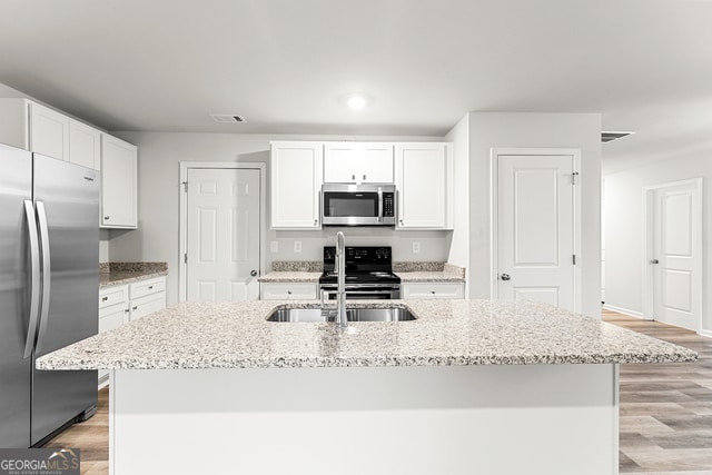 kitchen featuring white cabinets, appliances with stainless steel finishes, and a kitchen island with sink