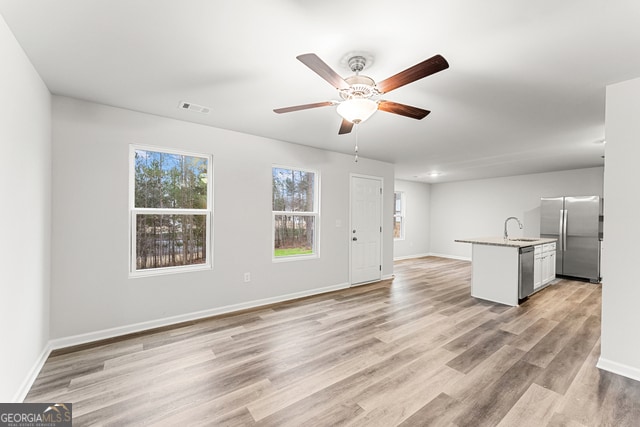 unfurnished living room featuring ceiling fan, sink, and light hardwood / wood-style floors