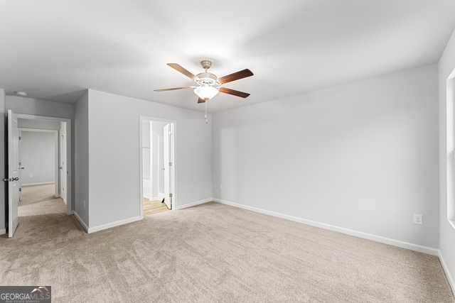 unfurnished bedroom with ceiling fan, light colored carpet, and ensuite bathroom