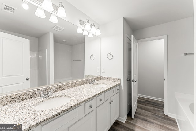 bathroom with a tub, hardwood / wood-style floors, and vanity