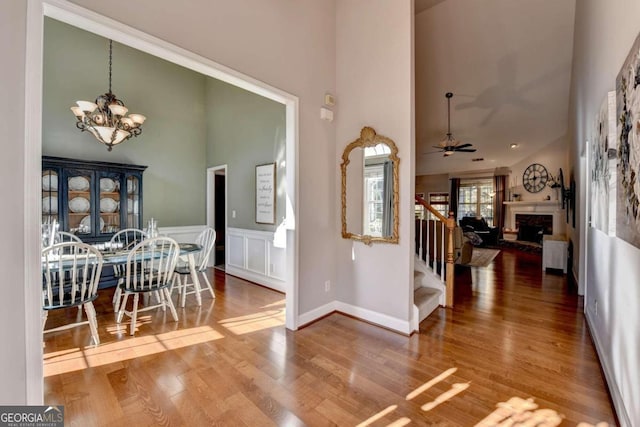 entrance foyer featuring ceiling fan with notable chandelier, a high ceiling, and hardwood / wood-style flooring