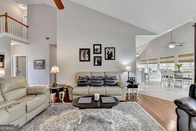 living room with ceiling fan, light wood-type flooring, and high vaulted ceiling