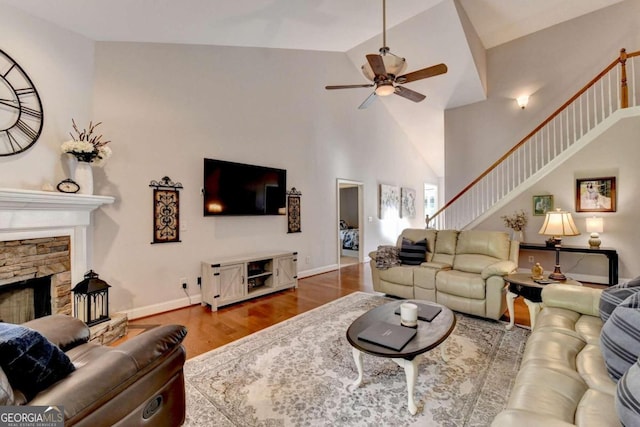 living room featuring hardwood / wood-style flooring, a fireplace, ceiling fan, and vaulted ceiling