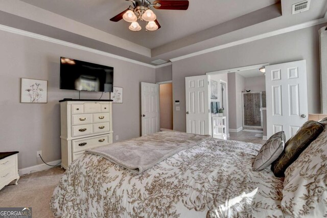 carpeted bedroom with a tray ceiling, ensuite bath, and ceiling fan