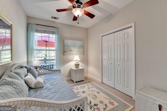 bedroom featuring light colored carpet, ceiling fan, and a closet