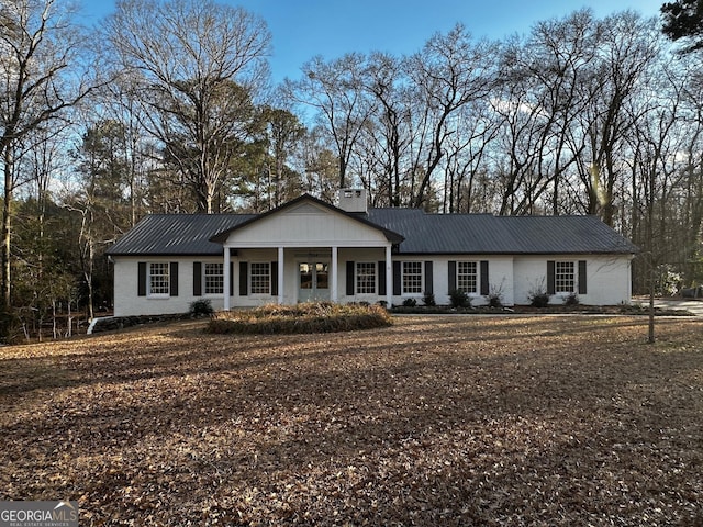 view of front of house with brick siding, metal roof, and a chimney