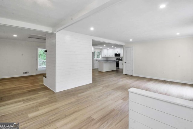 living room featuring beamed ceiling and light wood-type flooring