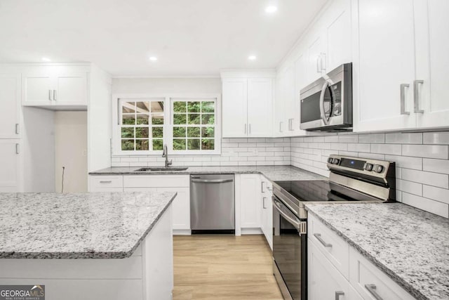 kitchen featuring sink, light stone countertops, white cabinets, and stainless steel appliances