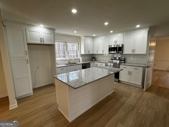 kitchen featuring a sink, stainless steel appliances, wood finished floors, and white cabinetry