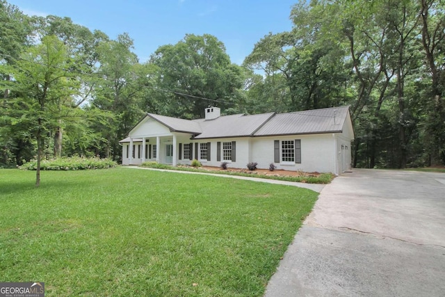 single story home with driveway, metal roof, a chimney, and a front lawn