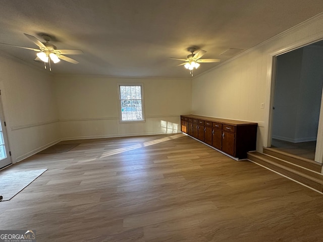 unfurnished room featuring a ceiling fan, crown molding, baseboards, and wood finished floors